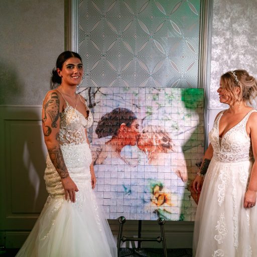 The brides standing beside their finished Mosaic wall photo